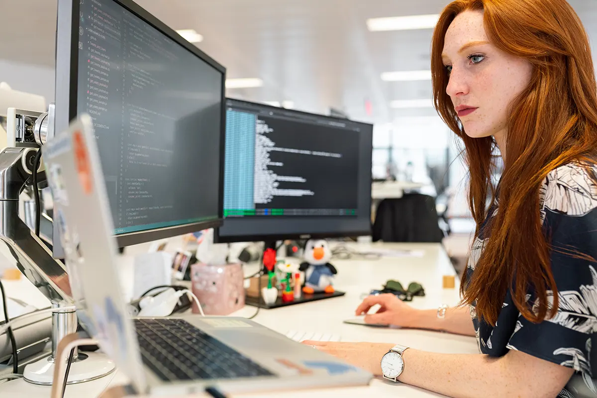 donna con i capelli rossi davanti a schermi del computer