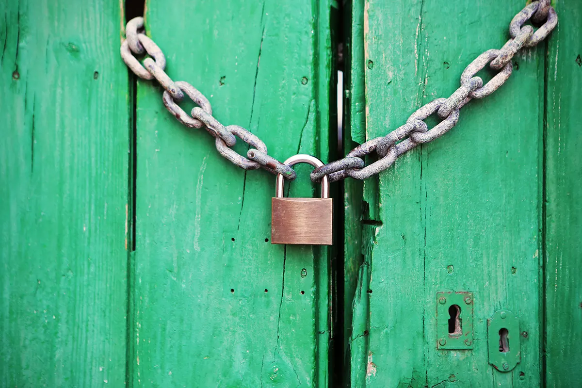 porta di legno verde chiusa con una catena e un lucchetto